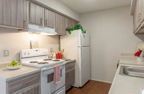 a kitchen with white appliances and wooden flooring and a white refrigerator